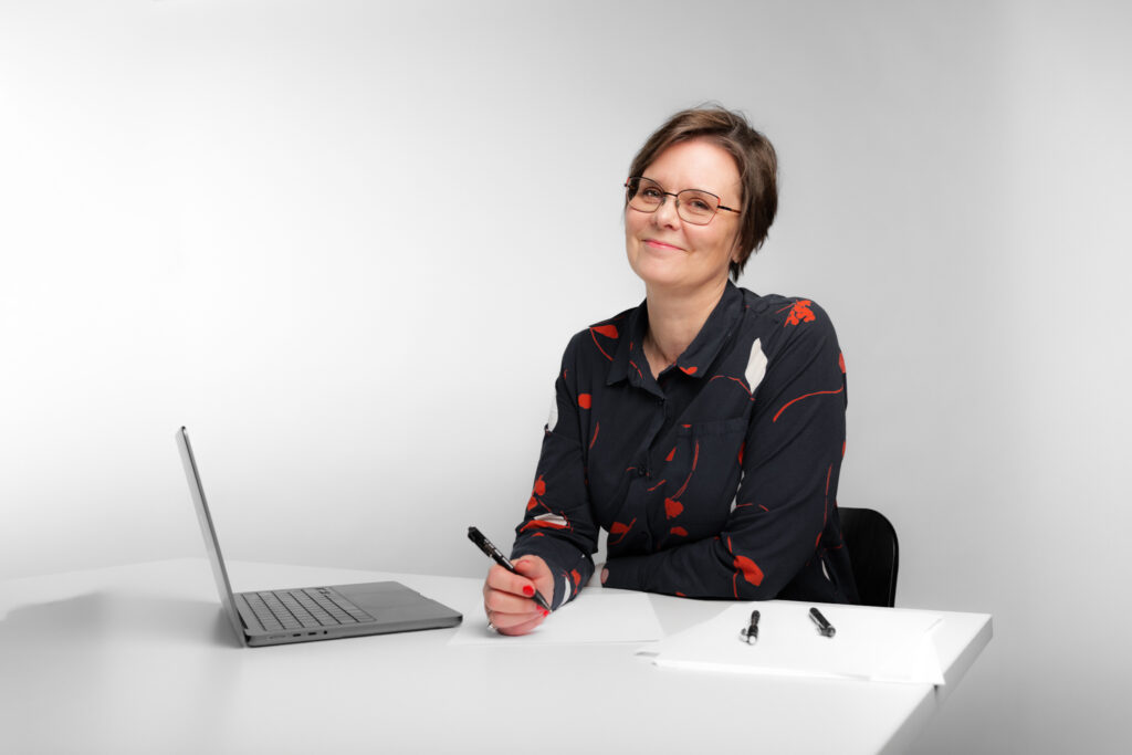 Henkilö istuu työpöydän ääressä kirjoittamassa.